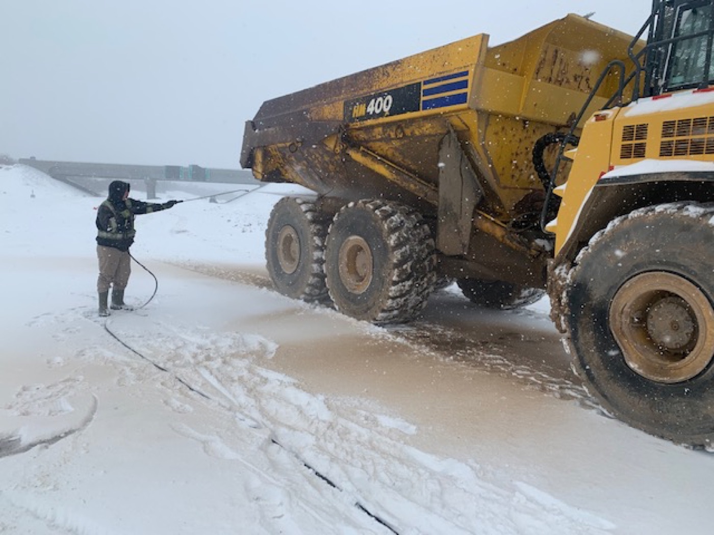 An O'Brien's operator pressure washing quarry mud off a haul truck at a Nova Scotia job site