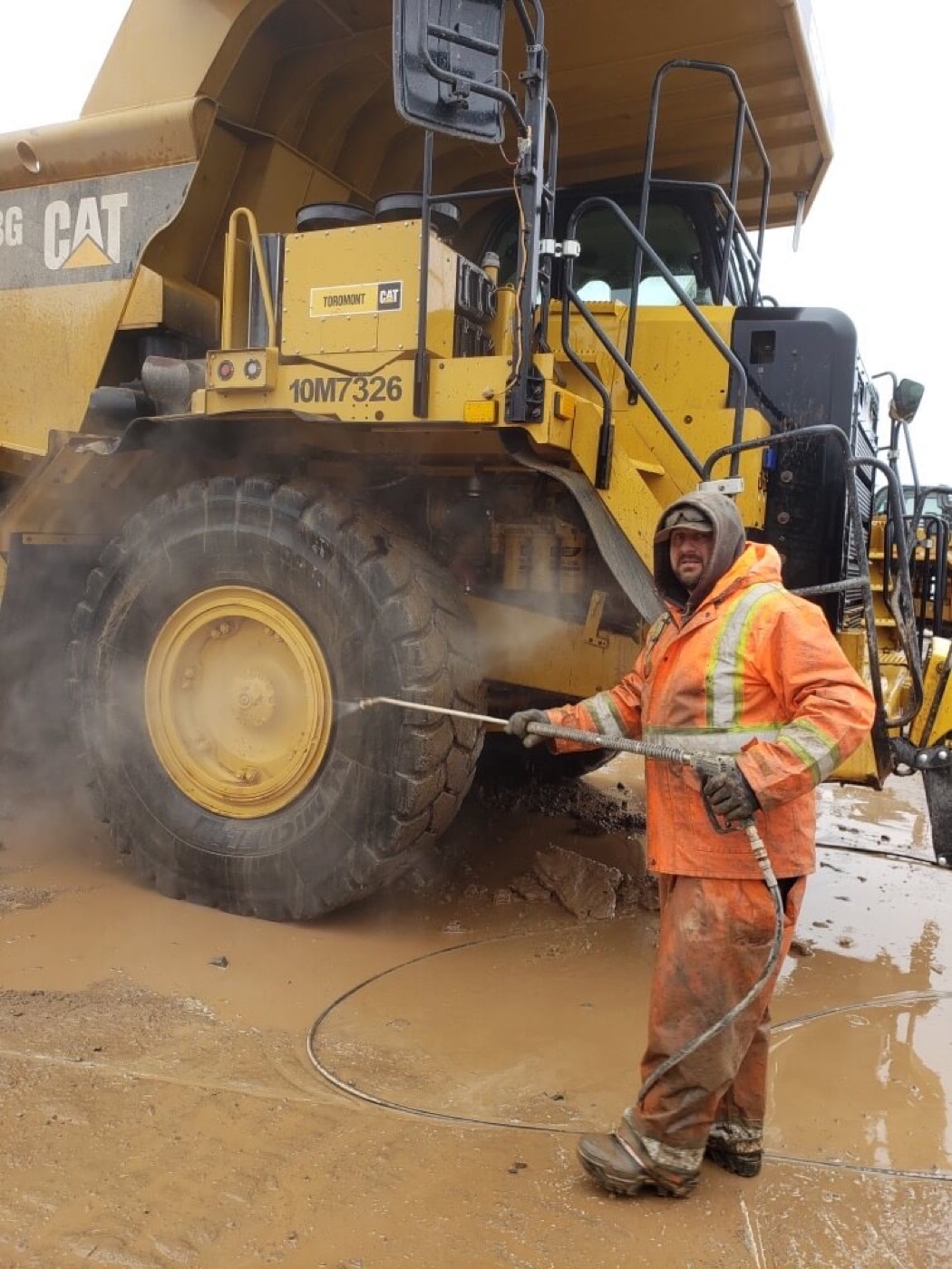 A wheel loader being pressure washed on site by O'Brien's Faster Blaster
