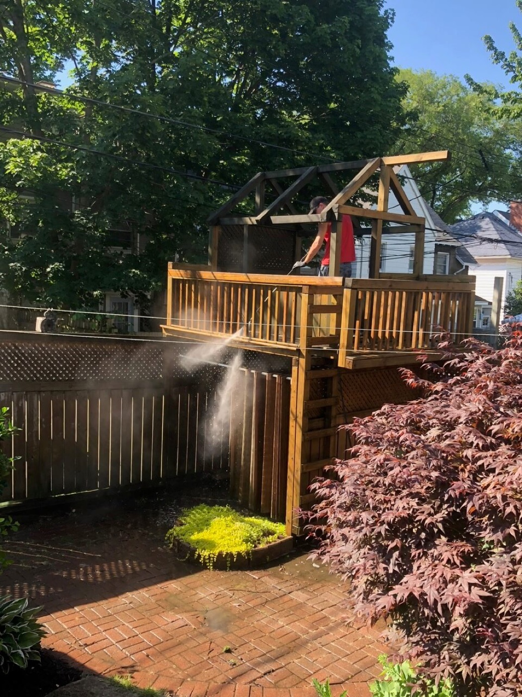 A wooden deck part way through being washed, clean boards beside grey ones