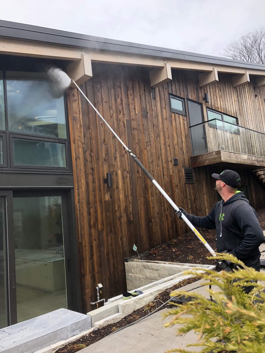 A wood sided building being soft washed at low pressure